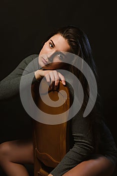 Sad brunette girl sitting in studio during model tests, dressed