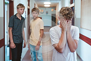 Sad bullied boy standing n the school corridor