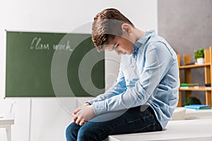 Sad and bullied schoolchild sitting on