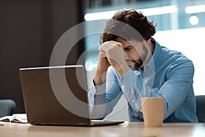 Sad business man grabbing head using laptop