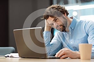 Sad business man leaning head on hand using pc