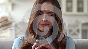 Sad business woman looking mobile phone at home office. Girl checking phone.