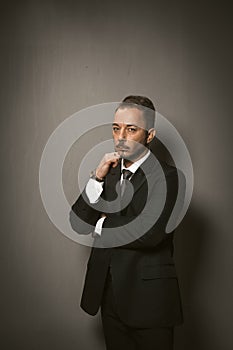 Sad businessman looks at camera feeling stress in crisis period. Serious caucasian man in black suit touches his chin