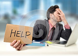 Sad businessman at office desk working on computer laptop asking for help depressed