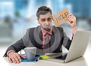 Sad businessman at office desk working on computer laptop asking for help depressed