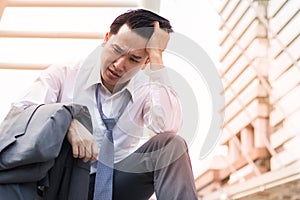 Sad businessman with suit sitting at stair walk way in city after business project fail