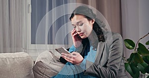 Sad businesswoman text messaging on mobile phone at home