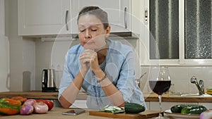 Sad casual lady holding glass of red wine while checking social media on the mobile phone at the cuisine