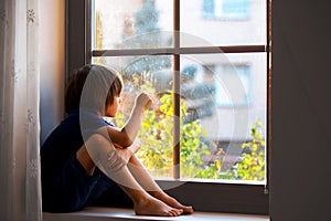 Sad child, boy, sitting on a window shield