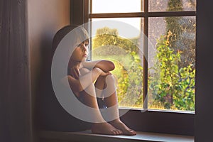 Sad child, boy, sitting on a window shield