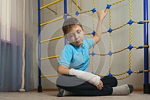 Sad child with a broken arm in the home environment . The cast on the hand of a little boy