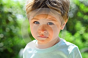 Sad child, close-up portrait. A frustrated child without mood. Sad emotions on a beautiful face. Child in nature