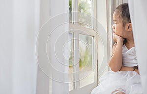 Depressed Little girl near window at home