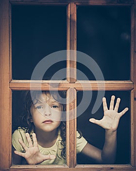 Sad child looking out the window photo