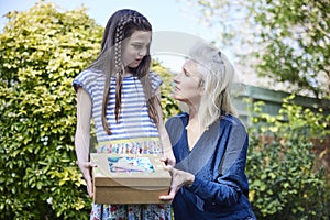 Sad Child With Mother Burying Pet Guinea Pig In Garden At Home