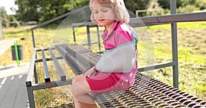 Sad child outdoors with a broken limb small, injured boy.