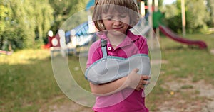 Sad child outdoors with a broken limb small, injured boy.