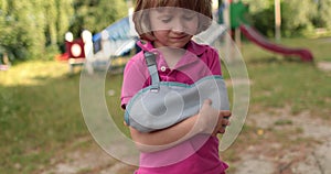 Sad child outdoors with a broken limb small, injured boy.