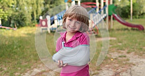 Sad child outdoors with a broken limb small, injured boy.