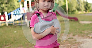 Sad child outdoors with a broken limb small, injured boy.