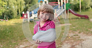 Sad child outdoors with a broken limb small, injured boy.