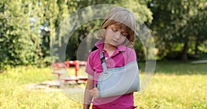 Sad child outdoors with a broken limb small, injured boy.