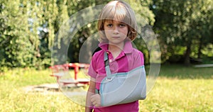 Sad child outdoors with a broken limb small, injured boy.