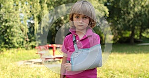 Sad child outdoors with a broken limb small, injured boy.
