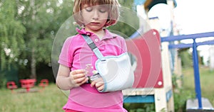 Sad child outdoors with a broken limb small, injured boy.