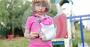 Sad child outdoors with a broken limb small, injured boy.