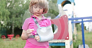 Sad child outdoors with a broken limb small, injured boy.