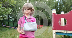 Sad child outdoors with a broken limb small, injured boy.