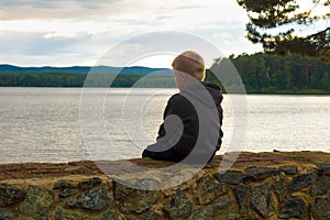 Sad child sitting at the lake