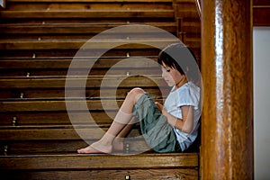 Sad child, sitting on a staircase in a big house, concept for bullying