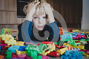 Sad child, stress and depression, exhaustion with toys scattered around