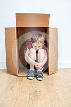 Sad child thinking hunched in a box, away from shyness