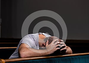 A Sad Christian man in white shirt is sitting and praying with humble heart in the church