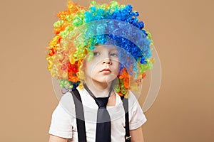 Sad clown boy with large colorful wig.