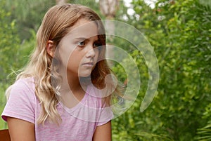 Sad, contemplative girl portrait with greenery in the background