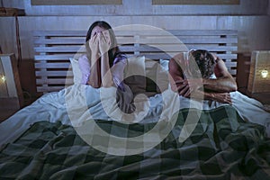 Sad couple after domestic fight with depressed woman crying and frustrated boyfriend sitting on bed unhappy in relationship stress