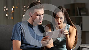 Sad couple reading bad news in a letter in the night