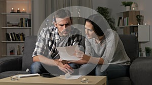 Sad couple reading a letter in the night at home