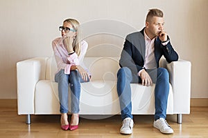 Sad couple sitting on couch and looking in different directions