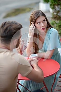 Sad couple sitting in open air cafe, having argument