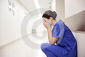 Sad or crying female nurse at hospital corridor