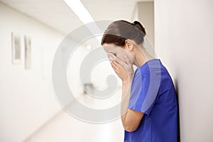 Sad or crying female nurse at hospital corridor