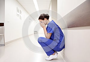 Sad or crying female nurse at hospital corridor