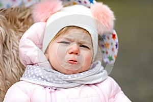 Sad crying hungry baby girl sitting in the pram or stroller on cold day