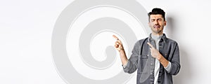 Sad crying man pointing fingers left at logo, sobbing and whining, being jealous or upset, standing on white background