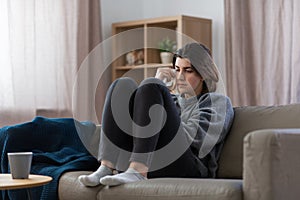 sad crying woman sitting on sofa at home